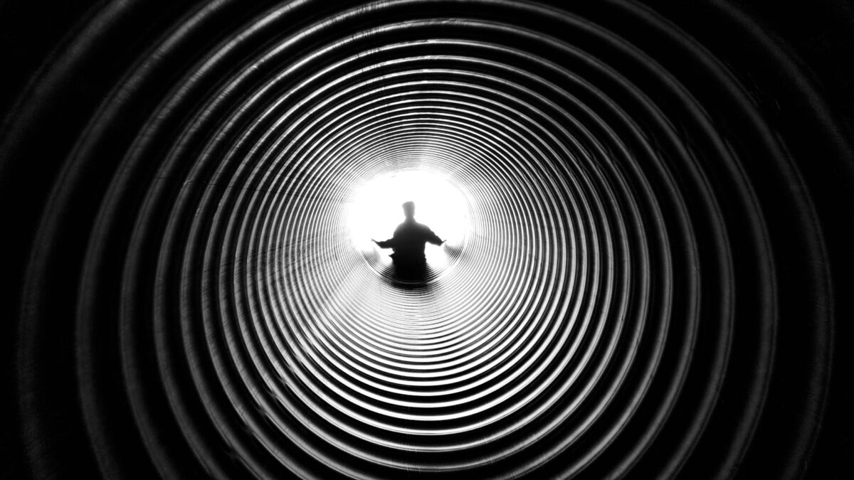 grayscale photography of person at the end of tunnel