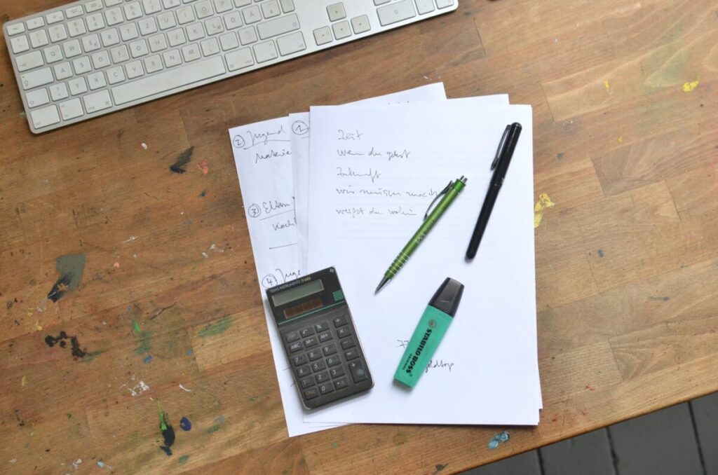 calculator and pens with marker placed on papers